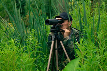 male ornitologist makes observations in the wild with a spotting scope