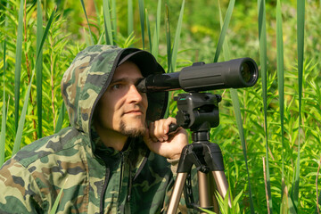 Fototapeta premium man ornitologist makes observations in the wild with a spotting scope