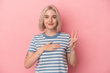 Young caucasian woman isolated on pink background taking an oath, putting hand on chest.