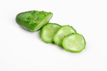 The cut cucumber with the knife on the white table