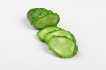 The cut cucumber with the knife on the white table