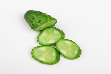 The cut cucumber with the knife on the white table