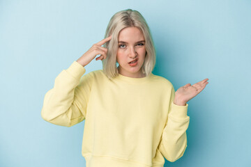 Young caucasian woman isolated on blue background showing a disappointment gesture with forefinger.