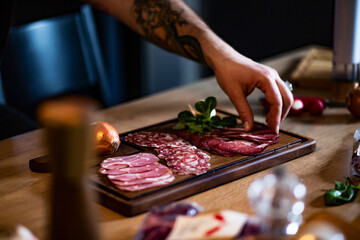 Food concept; Chef decorate ready dish with slices salami.
Young man with tattoo decorate delicious...