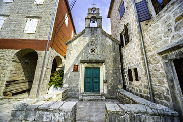 Fototapeta na wymiar Small old stone church between two bigger buildings,Perast,Montenegro.
