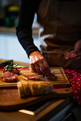 Food concept; Chef decorate sandwiches with slices salami.
Young woman making delicious snack...