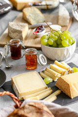 repas de différents fromages accompagné de confiture raisin et vin rouge sur une table