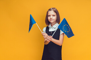 Schoolgirl holding two small European Union flags in her hands. Education in Europe concept 