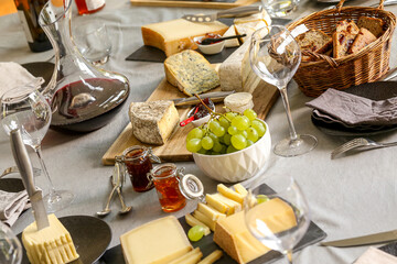 repas de différents fromages accompagné de confiture raisin et vin rouge sur une table - obrazy, fototapety, plakaty