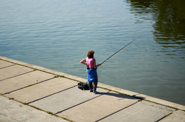 Grandma is fishing on the embankment