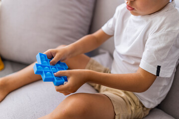 Little blonde boy children play with new trend sensory toy blue pop it. Antistress toy for children and adult.Colorful toy simple dimple. Squishy soft bubble toys blue color