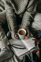 Winter still life concept. Young girl holding cacao mug, reading book. Season holiday, hygge concept