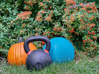 iron kettlebell, rubber slam ball filled with sand and pumpkin in a backyard, home gym, exercise...