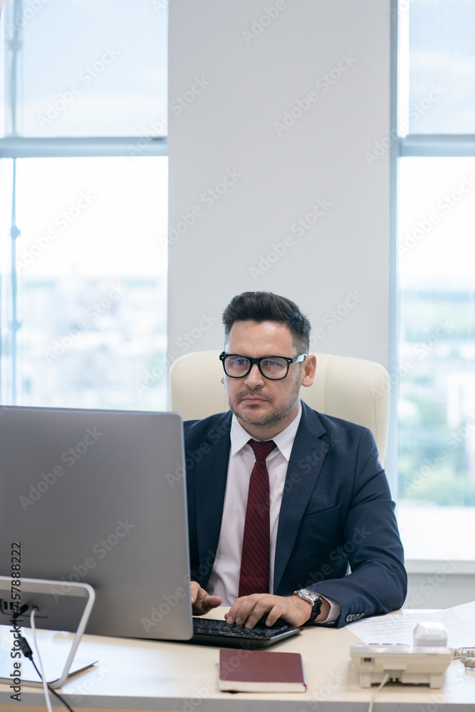 Aufkleber Busy man in formalwear typing on computer keyboard while sitting by desk in front of monitor