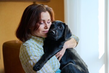 Portrait of middle aged woman and black labrador puppy dog