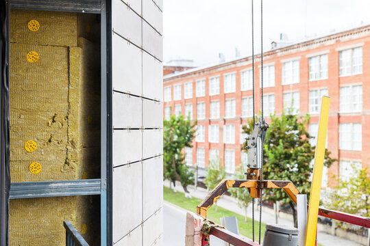 Installation of ventilated facade tiles and insulation on the building. Construction and insulation of buildings.