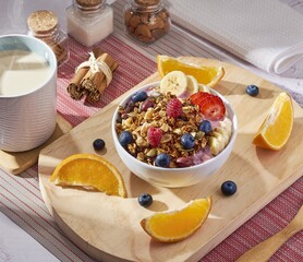 Desayuno con Bowl de granola artesanal con frambuesas, arándanos, naranja, fresas y plátano con taza de café 