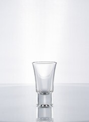 Vaso de cristal con forma para shots de tequila o vodka en fondo blanco gris 