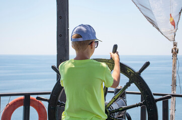 Obraz premium boy is at the helm of a ship at sea