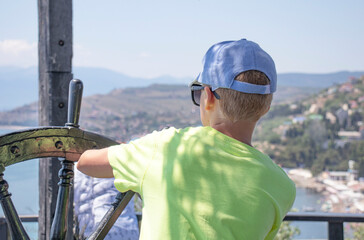 boy is at the helm of a ship at sea