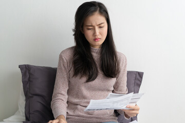 stressed young asian woman calculating monthly expense and checking credit card bills invoice.