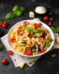 King prawn pasta salad with marinated green olives, cherry tomatoes and parmesan cheese shavings. Healthy food.
