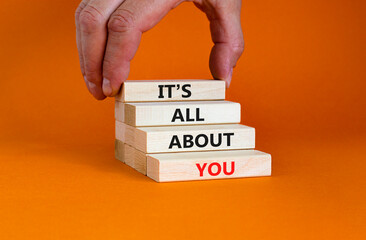 It is all about you symbol. Wooden blocks with words 'It is all about you'. Beautiful orange background. Businessman hand. Copy space. Business and it is all about you concept.