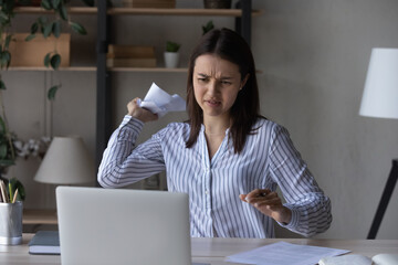 Annoyed frustrated businesswoman throwing crumpled papers at laptop screen, angry young woman...