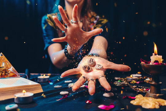 Astrology and esoterism. A sorcerer holds a flaming stones with the sign of the zodiac. Close up. The concept of horoscopes and telling