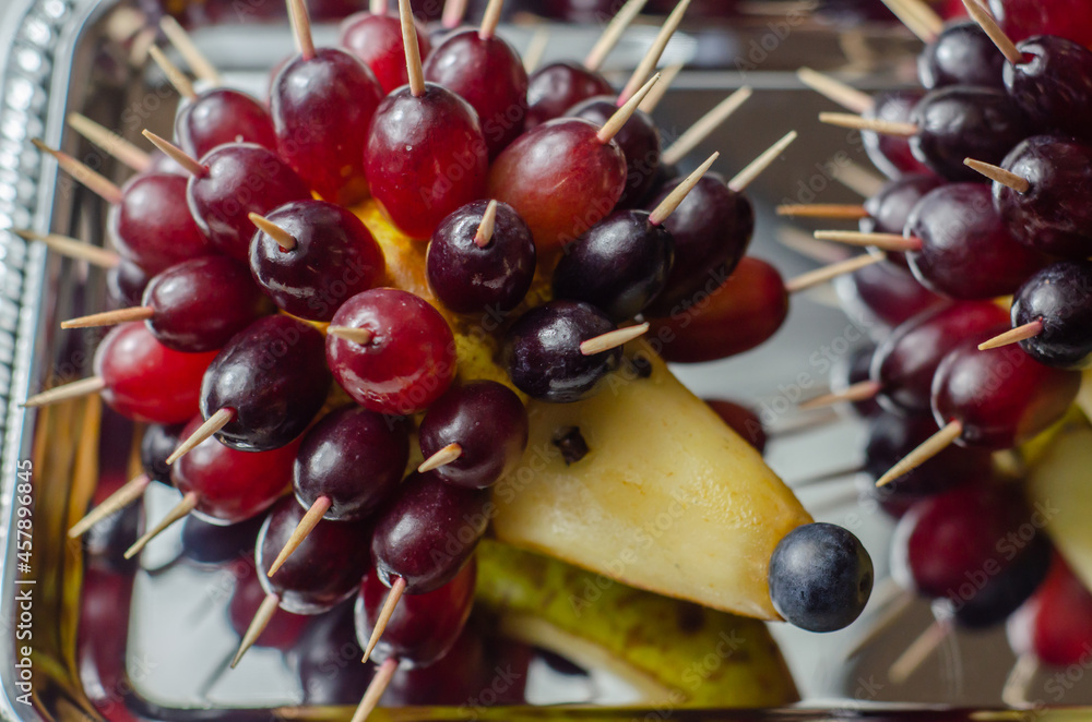 Wall mural fruit hedgehog, red grapes and juicy pear, creative way of serving fruit