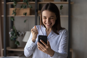 Excited smiling young woman looking at phone screen, celebrating good news, reading message in...