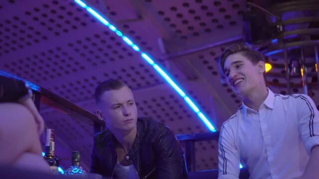 Guys and girls relax at a table in a nightclub. They laugh, drink, talk . A party. Alcoholism. the guy gets sick after drinking. poisoning. dizziness. The harm of alcohol on the body. Clofelin