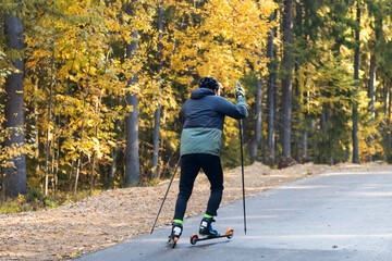 A man on a roller ski rides in the park.Cross country skilling.