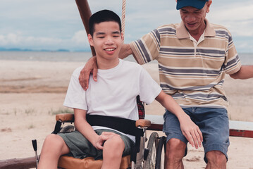 Happy disabled teenager boy smiling face with parent on outdoors activity at the beach, Vacation of people with disabilities and family in nature outside , Mental health concept. - obrazy, fototapety, plakaty