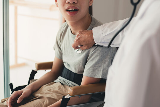 Hand of a kind docter checking heartbeat to asian handicapped teeager boy in examination room, People with disabilities activity in hospital or home for the disabled or quarantine, Healthcare concept.