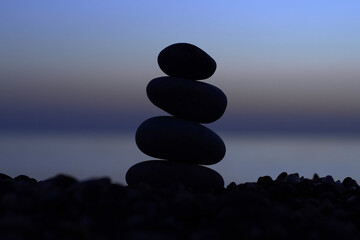 Pebble tower on the seaside at sunset. Pyramid of stones. Balanced zen stones.