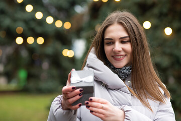 Merry lady holding a gift box at the street