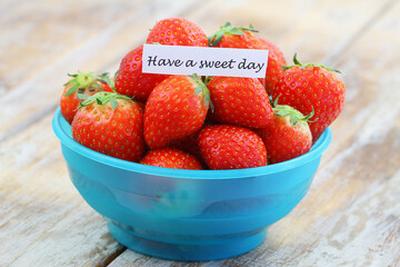 Have a sweet day note with fresh, sweet strawberries in blue plastic bowl

