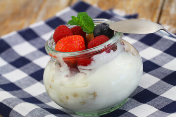 Healthy breakfast: bio yoghurt with granola, fresh strawberries, raspberries and blueberries in transparent glass
