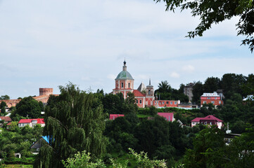 Fototapeta na wymiar Panoramic view of the city. View of the old church and the fortress wall. Private houses among the trees.