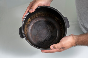 a man holding a non-stick pan with a damaged coating