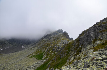 Fototapeta na wymiar Fog and rain clouds over high mountain peaks of the ridge at High Tatras mountains, Slovakia