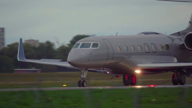 Business jet is taxiing on the runway after landing ay dusk. Side view