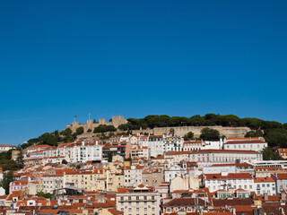 Fototapeta na wymiar Lisbon St George Castle on top of the hill with houses below and blue sky