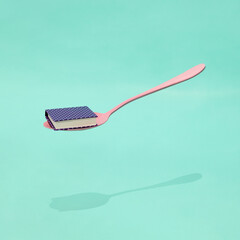 Creative educational concept. Minimal composition with book and spoon on mint background. Back to school idea.