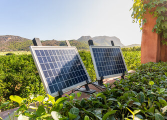 small solar panels illuminated by the sun, outside a garden. 