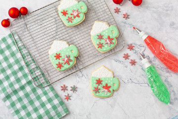 Homemade Christmas Cookies Shaped Like Coffe Mugs with Fondant Snowflkes; Piping Bags of Red and Green Icing