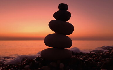 Pebble tower on the seaside at sunset. Pyramid of stones. Balanced zen stones.