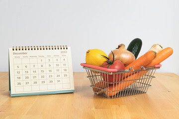 December 2022 calendar and vegetables in shopping basket - symbol of prices and inflation