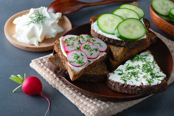 Sandwiches with soft cheese radish and cucumber on a wooden cutting Board. Healthy breakfast